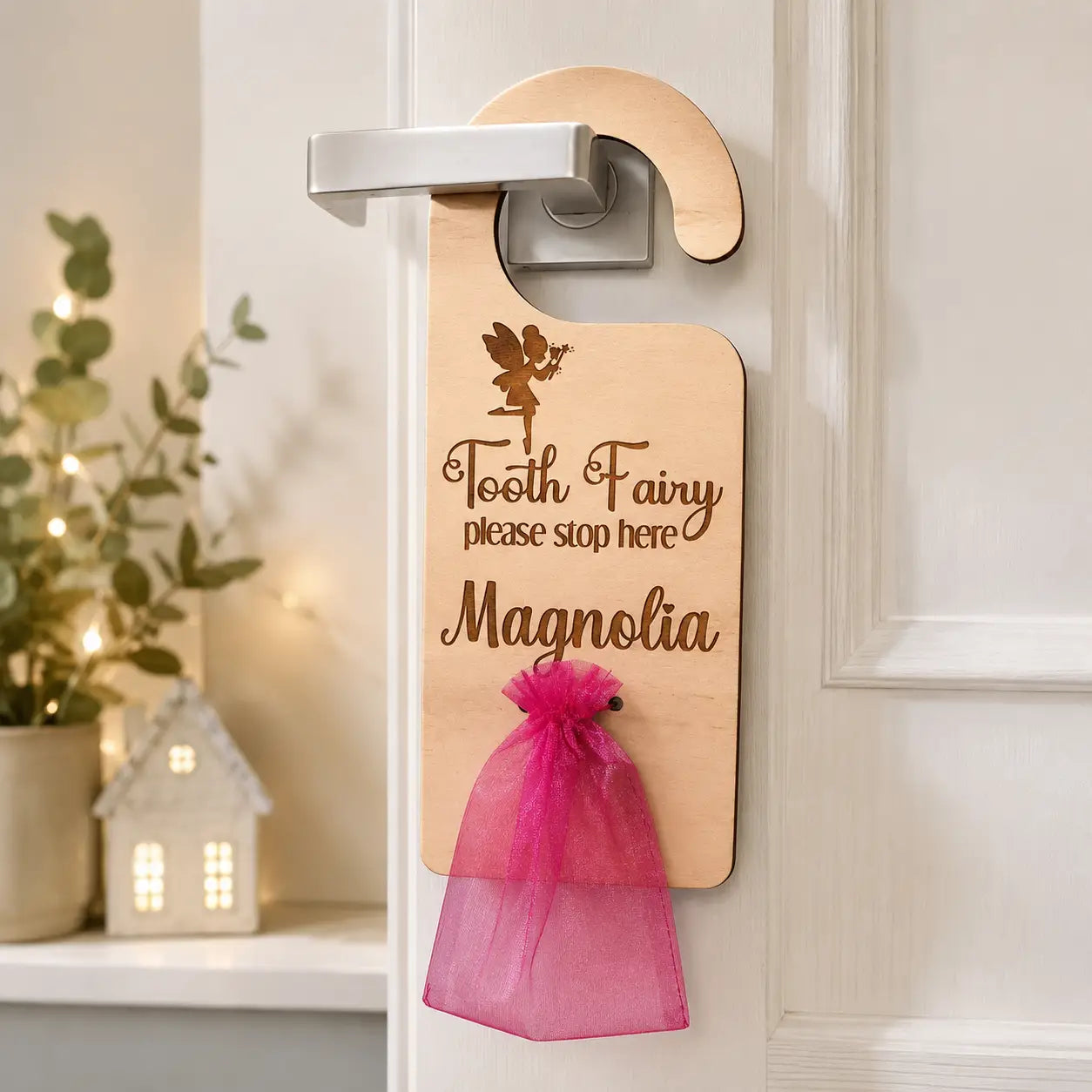 Handmade personalised tooth fairy door hanger engraved on natural timber with custom child name and pink tooth pouch, hanging on bedroom door for kids tooth fairy gifts and bedroom decor.
